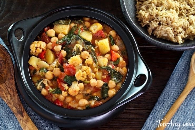 Overhead view of Curried Vegetable Stew with brown rice and wooden spoon.