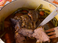 Savory grass-fed pot roast with vegetables in a pot, with a fork