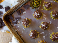 Dark chocolate covered pistachio balls arranged on a baking sheet