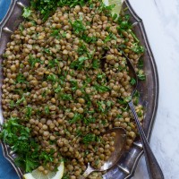 Vertical image of Lemon Lentil Parsley Salad on a long silver-like plate with spoons