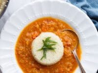 Moroccan vegetable soup with couscous, chickpeas, and lemon on a white plate with a spoon