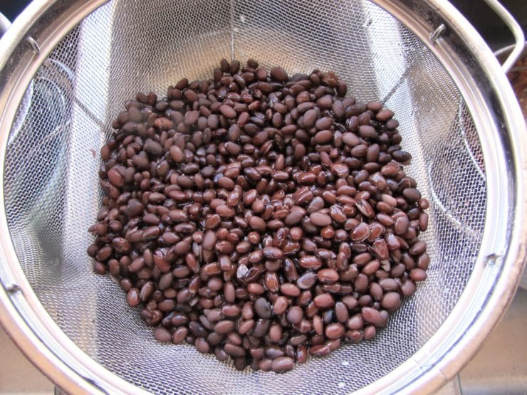 Black beans in a strainer by the sink