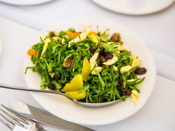 Colorful salad on a white plate on a white tablecloth.