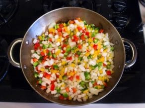Chopped vegetables in pan cooking on stovetop - peppers, onions.