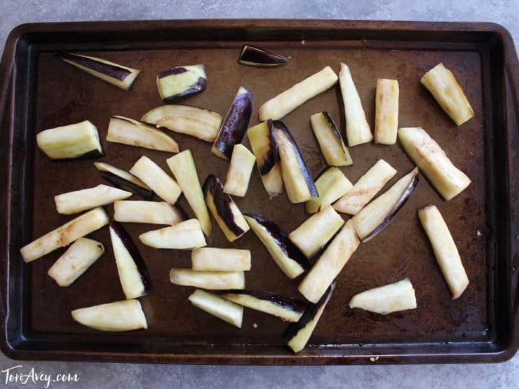Roasting eggplant slices on baking sheet to make mnazaleh, a traditional Middle Eastern Druze recipe.