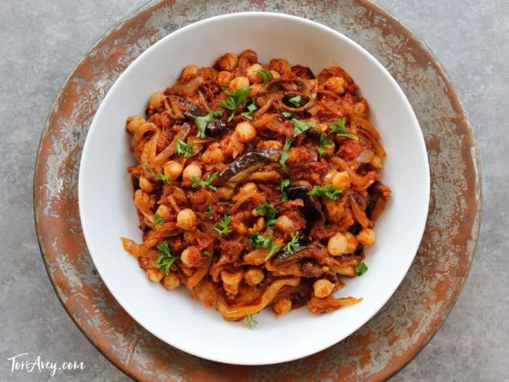 Mnazaleh - Chickpeas, Eggplant and Onions with Recipe in White bowl on metal platter.