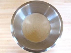 Stainless steel bowl of batter on a light wood background.