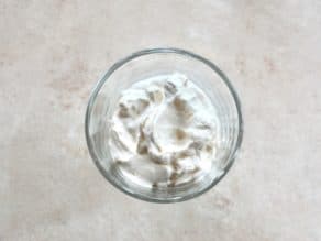 Whipped cream in dessert dish on light colored background.