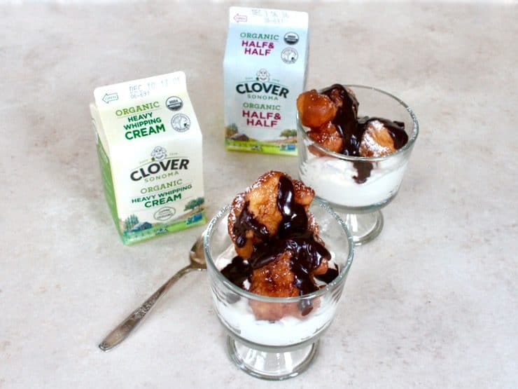 Two Hanukkah Fritter Sundaes in Glass Bowls with Spoon Next to a Small Container of Clover Organic Heavy Whipping Cream, and a Small Container of Clover Organic Half and Half.