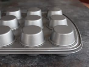 Two muffin tins, one inverted on top of the other, on grey countertop.