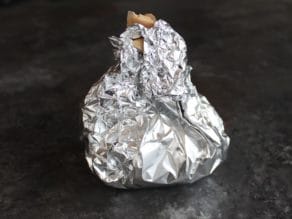 Garlic head wrapped up in foil and parchment packet.