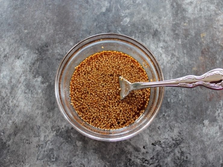 Marinade and cayenne in a small bowl, fork stirring marinade on countertop.