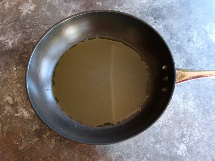 Nonstick skillet coated with olive oil on countertop.