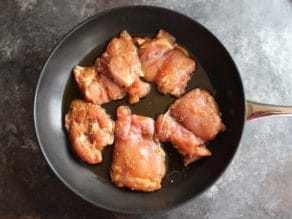 Uncooked Spicy Teriyaki Broiled Chicken Thighs in skillet with olive oil.