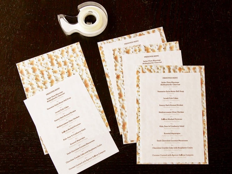 Paper menus on a black background next to a roll of tape.