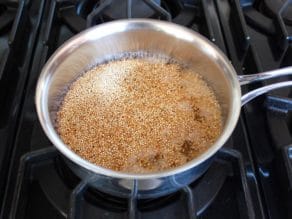 Simmering toasted quinoa in saucepan on stovetop.