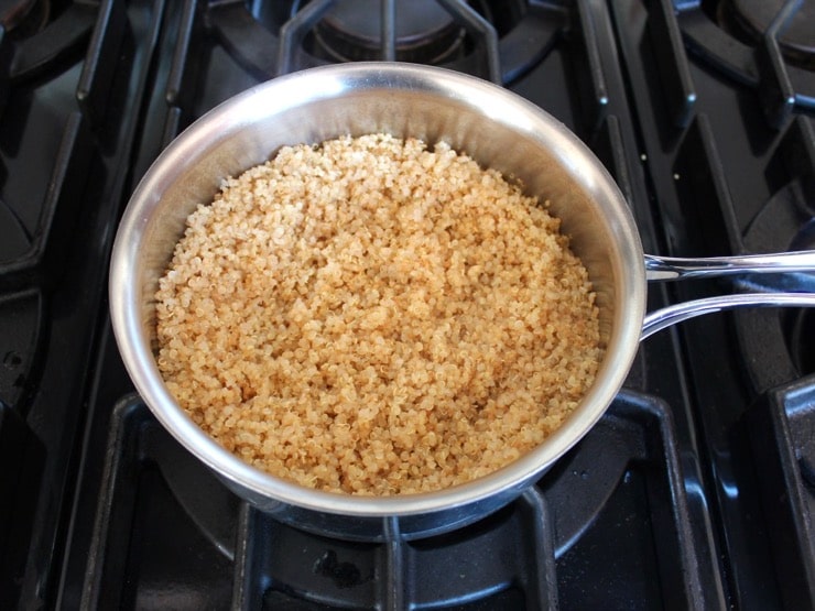 Fluffy steamed toasted quinoa in saucepan on stovetop.