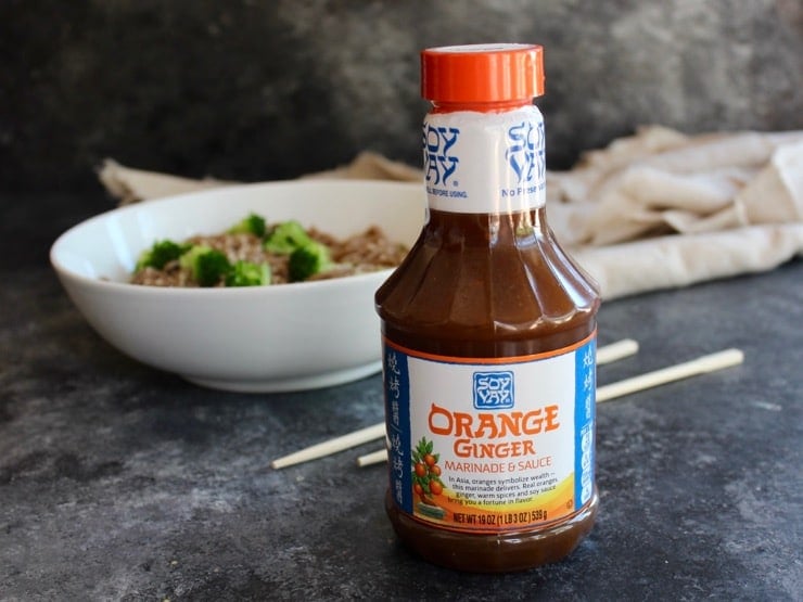 Bottle of Soy Vay marinade in foreground, Bowl of soba noodles with broccoli, chopsticks and cloth in background.