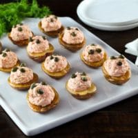 Overhead view of a tray of small roasted potatoes topped with a lox topping and garnished with capers