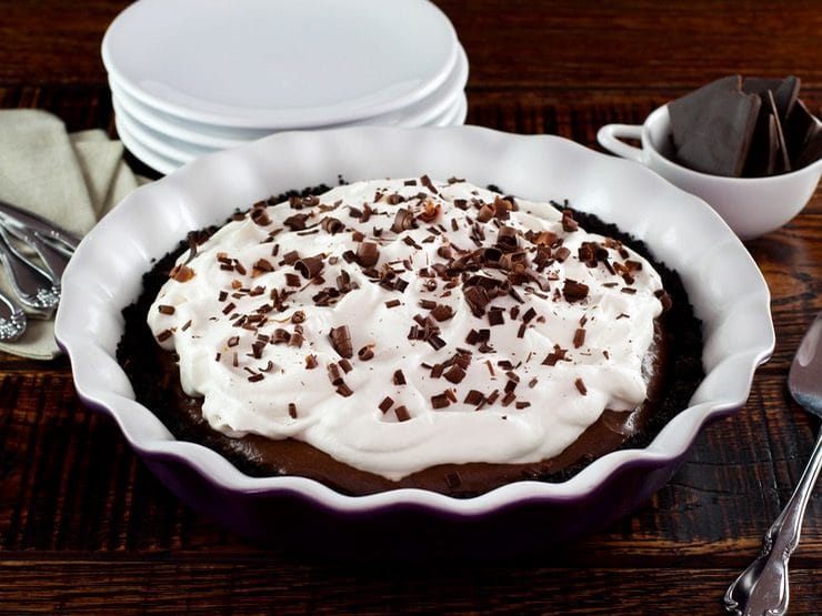 A whole pie topped with fluffy white whipped cream and brown chocolate shavings.