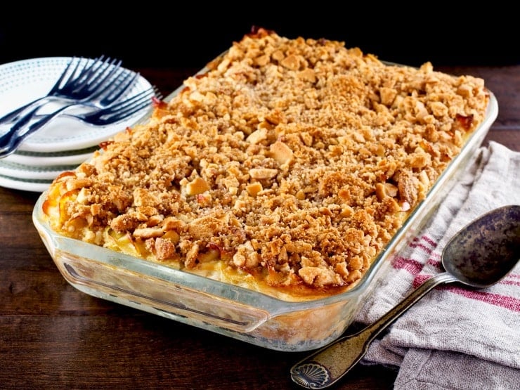 A large glass casserole dish filled with noodle kugel with a crunch cookie topping.