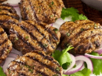 Grilled meat patties topped with onions and lettuce