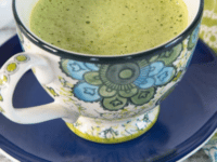 A creamy Matcha Green Tea Latte in a white cup on a wooden table