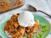 A delicious dessert made with oat nut topping and served with a scoop of creamy vanilla ice cream