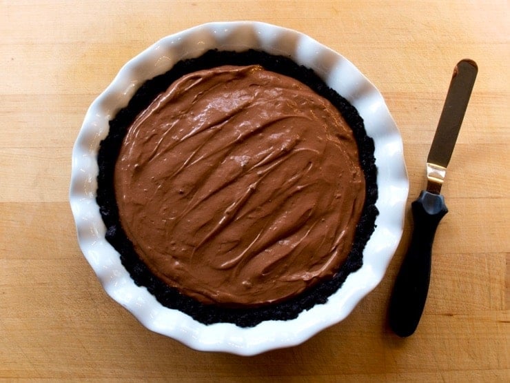 Chocolate filling inside of a chocolate crust in a white pie plate.