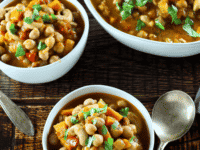Three bowls of Vegan Chickpea Chili stew with colorful vegetables and fresh herbs