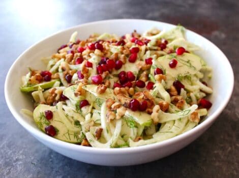 Close up of a bowl of Fennel Apple Salad with Cider Tahini Dressing, topped with pomegranate seeds.