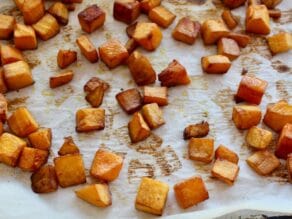 Roasted pieces of butternut squash sitting on a paper towel.