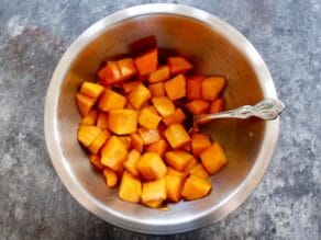 Diced pieces of butternut squash in a metal mixing bowl.