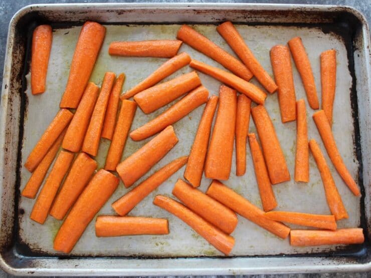 Uncooked sliced carrots on a baking sheet.