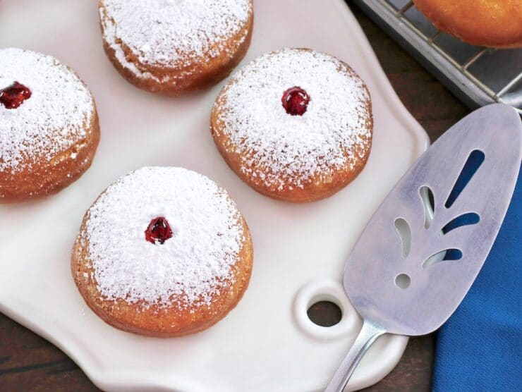 Overhead shot - close on platter of sufganiyot with decorative spatula.