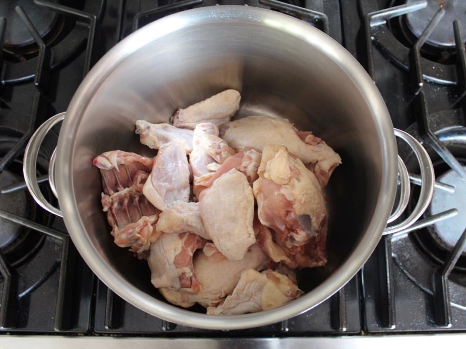 Raw chicken parts in pot on stovetop for chicken stock.