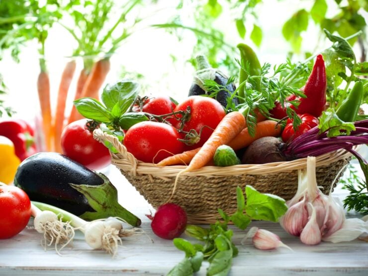 Horizontal image of a wicker basket filled with a bounty of fresh, colorful vegetables.