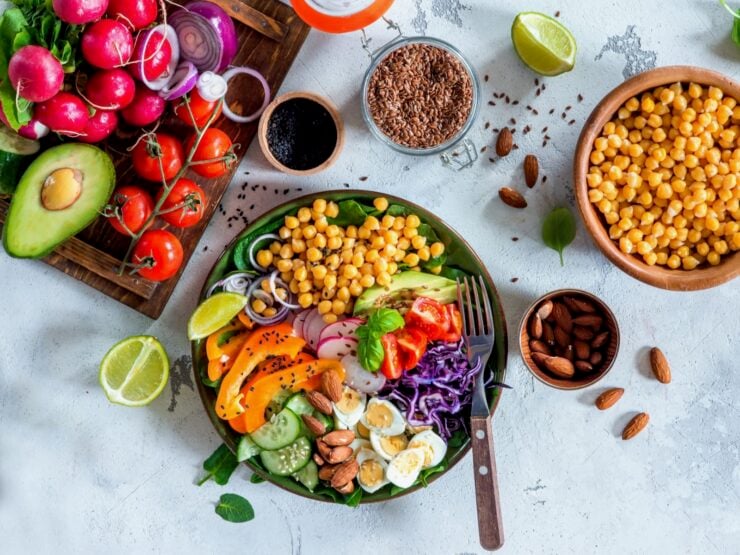 Horizontal image of plate filled with fresh, colorful vegetables next to a tray filled with more fresh, colorful vegetables.