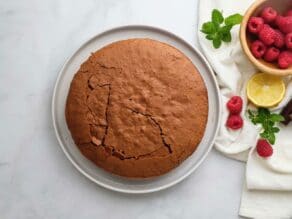 Overhead shot of a baked chocolate almond flour cake on a white plate.