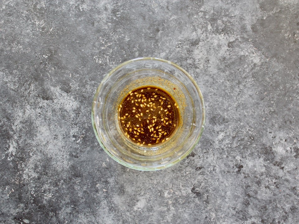 Small glass bowl with za'atar oil on a grey countertop.