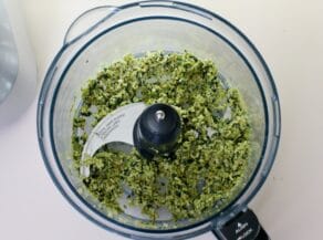 Overhead shot of food processor bowl filled with green tapenade.
