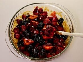Overhead shot of a glass bowl filled with a mixture of sliced berries tossed in sweetened balsamic vinegar dressing.