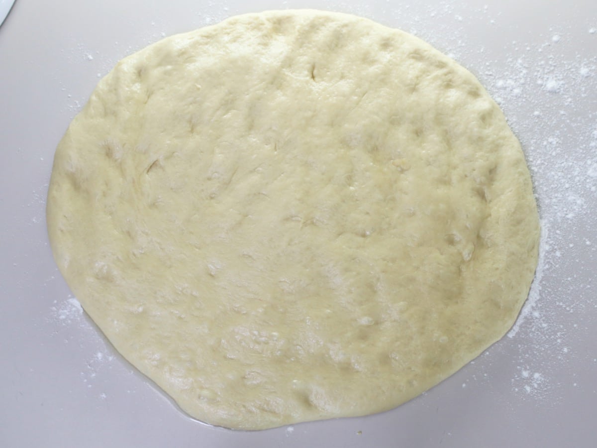 Overhead shot of challah dough flattened into a large circle.