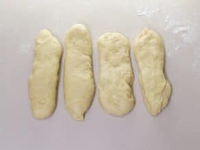 Overhead shot of challah dough separated into 4 rectangular pieces.