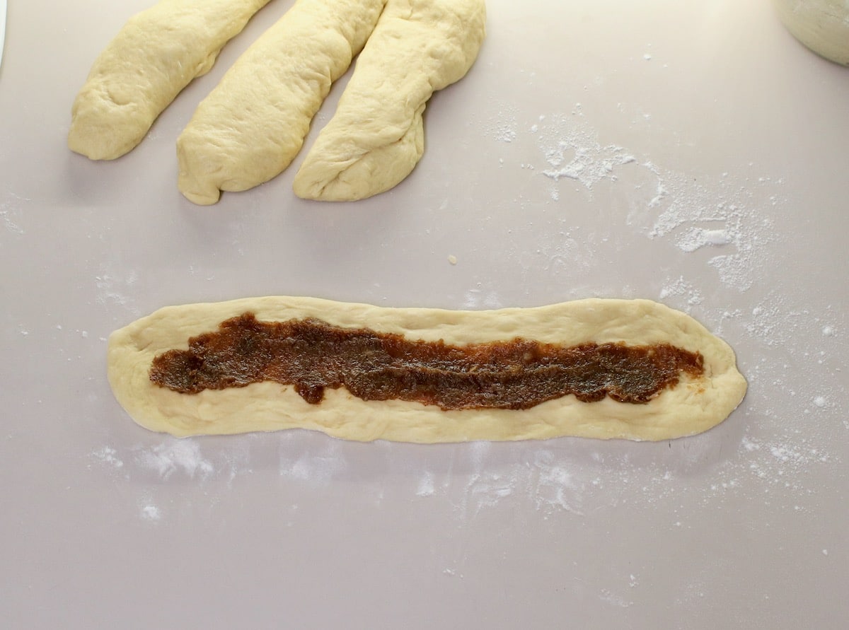 Overhead shot of a long strand of challah dough topped with date filling.