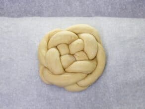 Overhead shot of challah dough braided into a circular loaf.