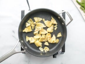 Horizontal overhead shot of artichoke hearts cooking in a sautée pan