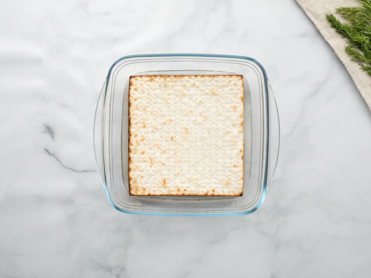 Horizontal overhead shot of a sheet of matzo in a square glass baking dish.