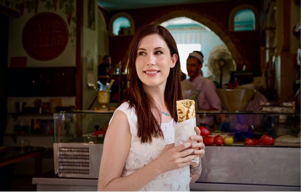 Image of Tori Avey holding a savory pita wrap, positioned on the left side of the image.
