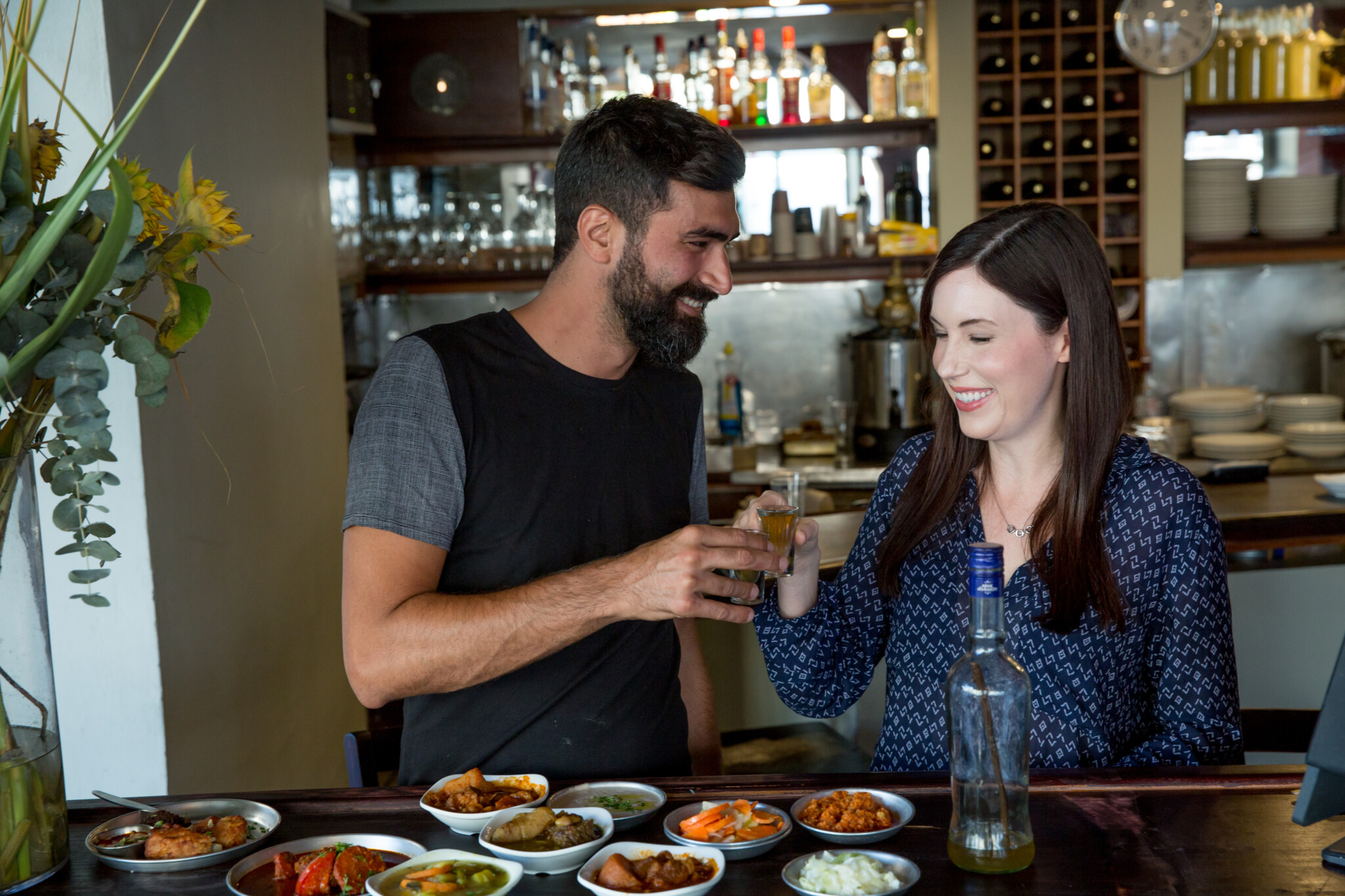 Tori Avey at Guetta Restaurant in Jaffa, Israel, toasting the owner of the restaurant over a table of many delicious Tripolitandishes.